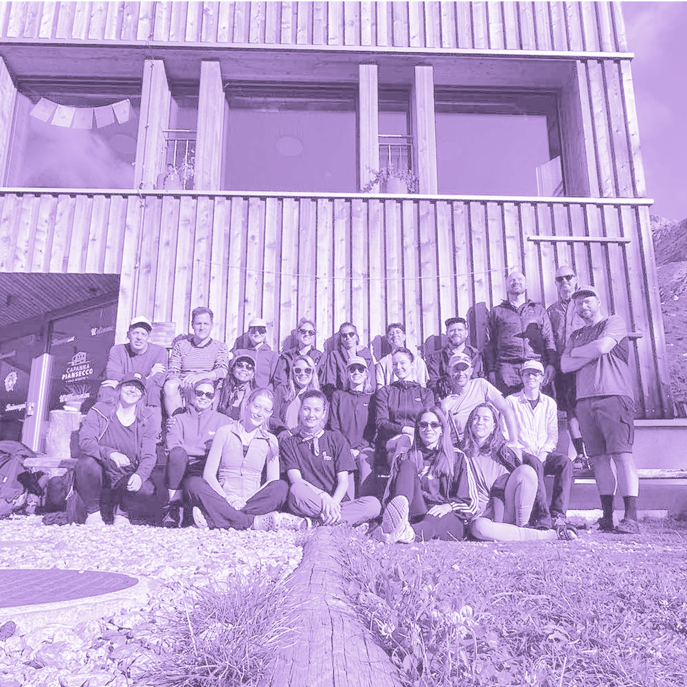 Group of people posing in front of a modern wooden building with large windows.
