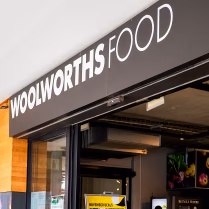 Entrance of Woolworths Food store with black and white signage above the door.