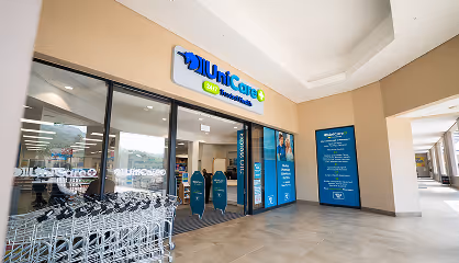 Entrance of UniCare facility with glass doors, shopping carts on the left, and informational posters on the walls.