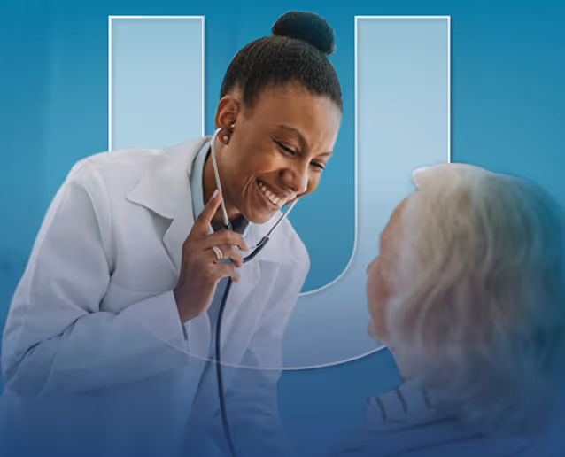 Smiling doctor using a stethoscope to listen to an elderly patient's chest.