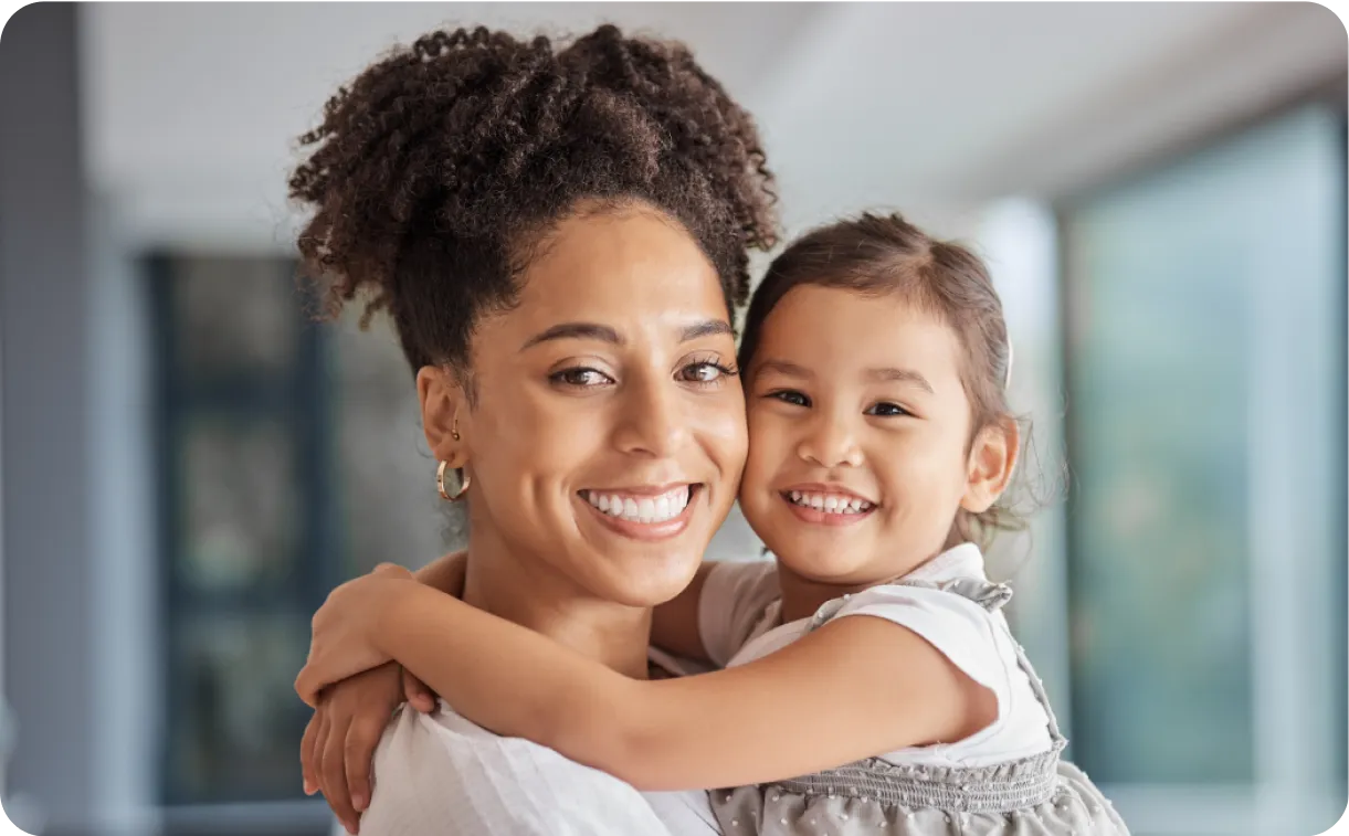 a woman holding a little girl in her arms. Both smiling