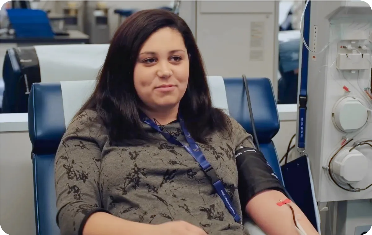 A woman with a cast on her arm, to donate plasma, sitting in a chair,