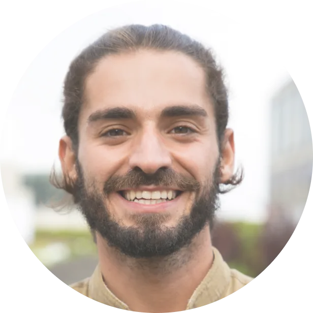 rounded picture of a man with long hair and a beard smiling