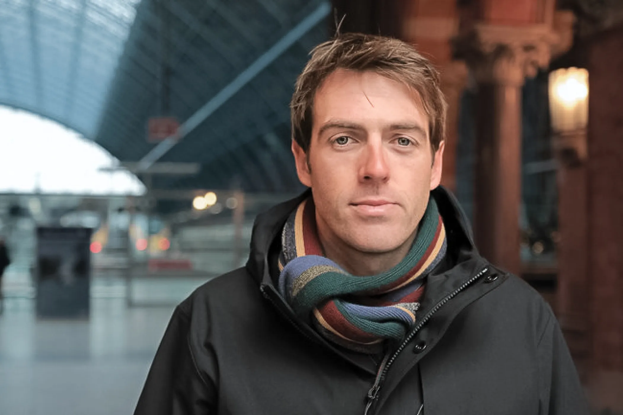 a young man with a scarf around his neck looking at the camera