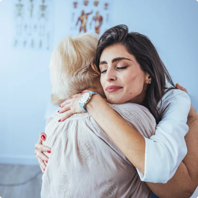 A lady and a women are hugging each other.