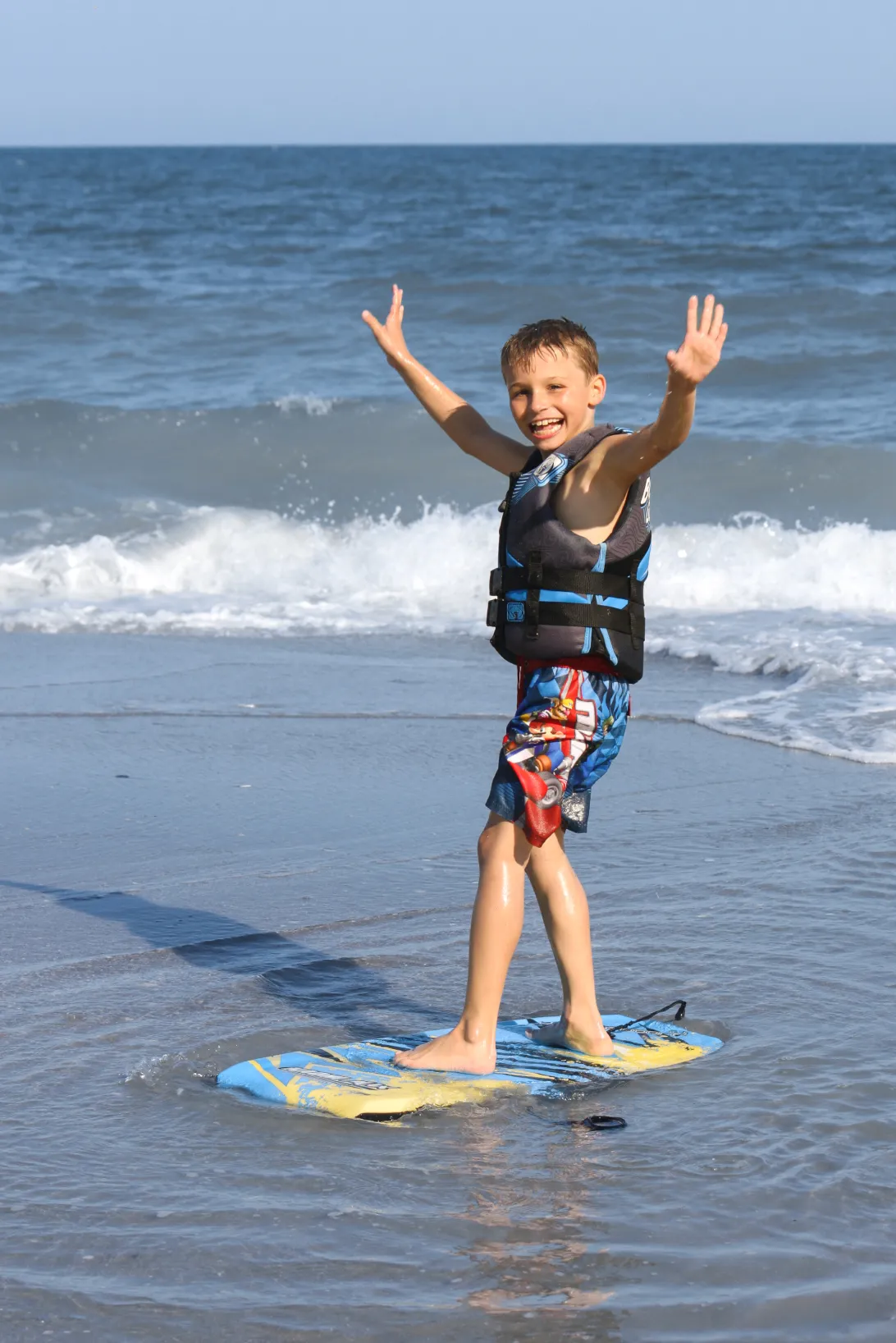 A little boy is standing on a surf desk.