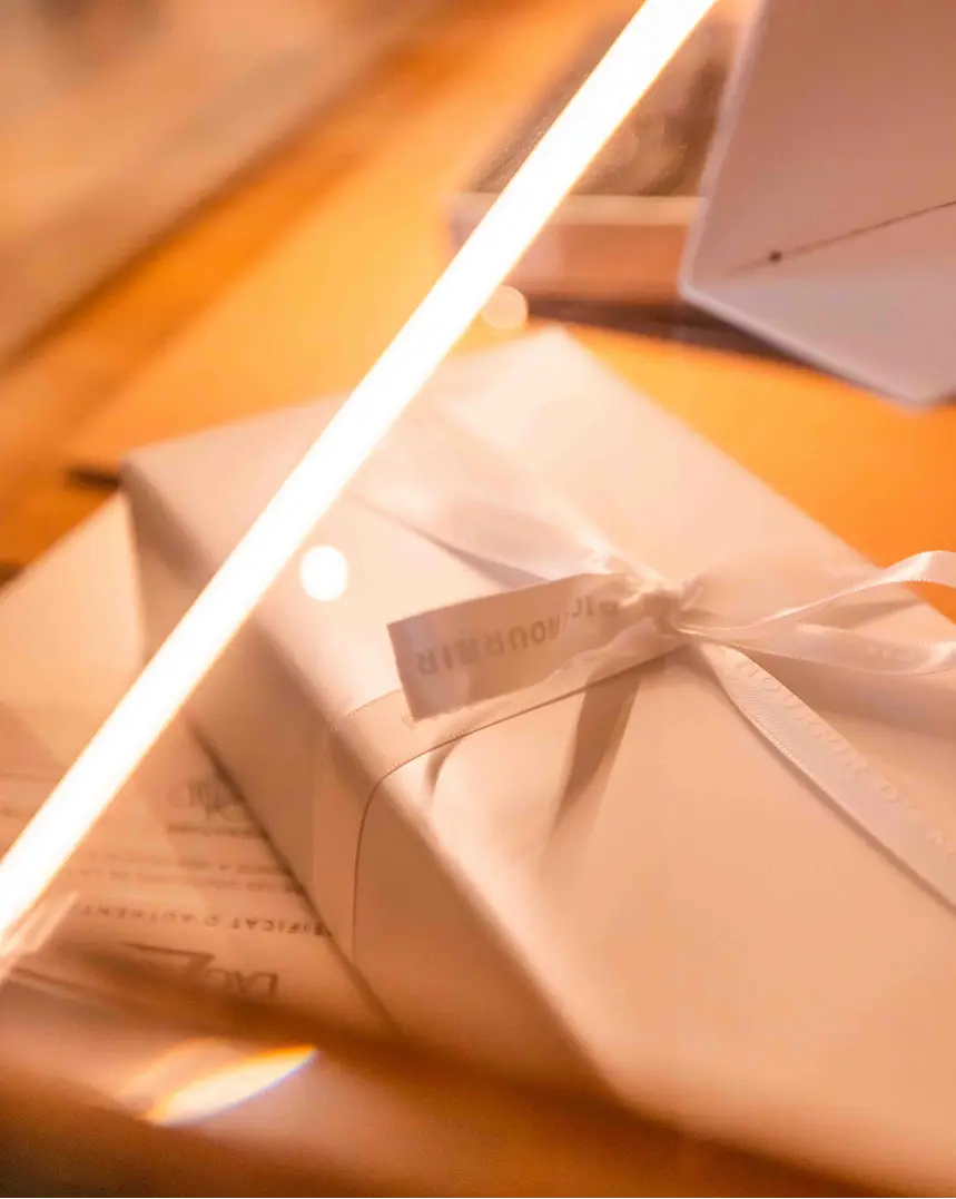 Gift wrapped with a white ribbon, placed on a wooden surface with warm lighting.