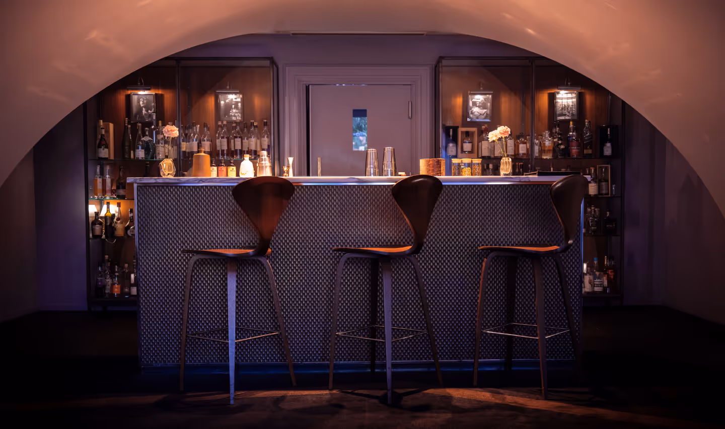 Le Bar Pic à Valence, avec trois tabourets en bois devant un comptoir texturé, éclairage tamisé sous plafond voûté.