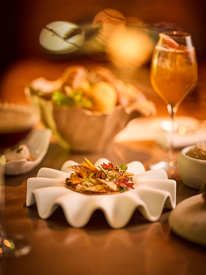 Weißes Gericht, dekoriert mit bunten Herbstblättern, in einer warmen Restaurantatmosphäre.