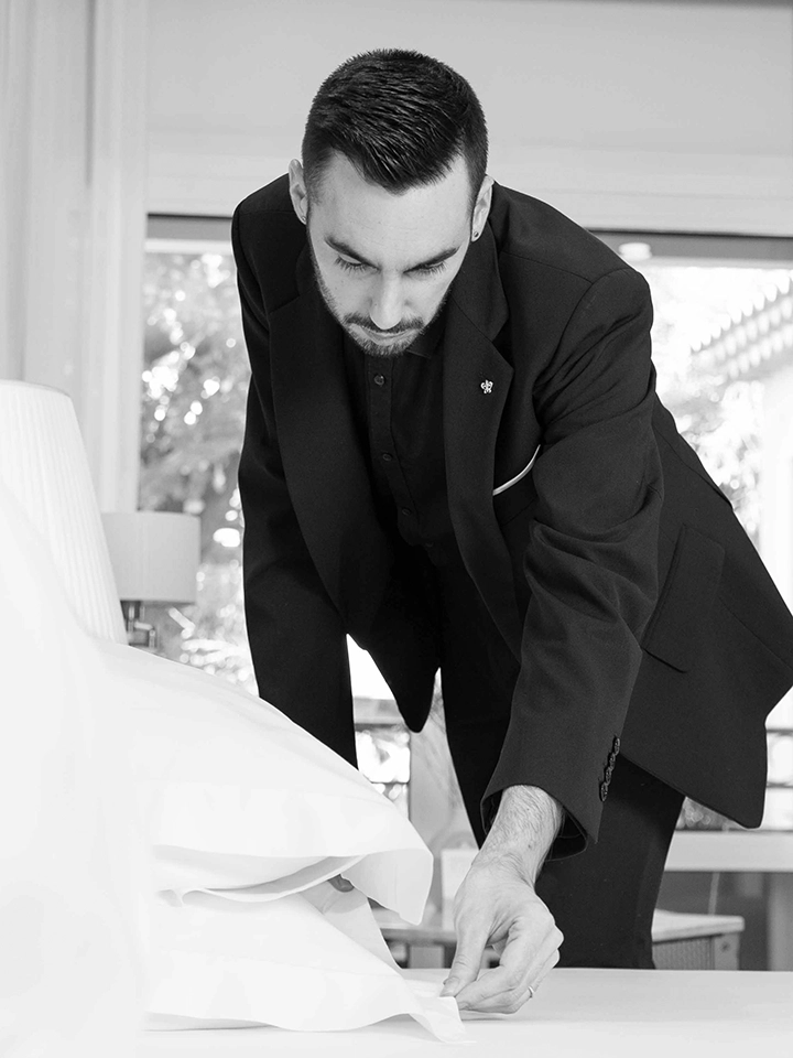 Un valet de chambre ajuste soigneusement les draps d'un lit.