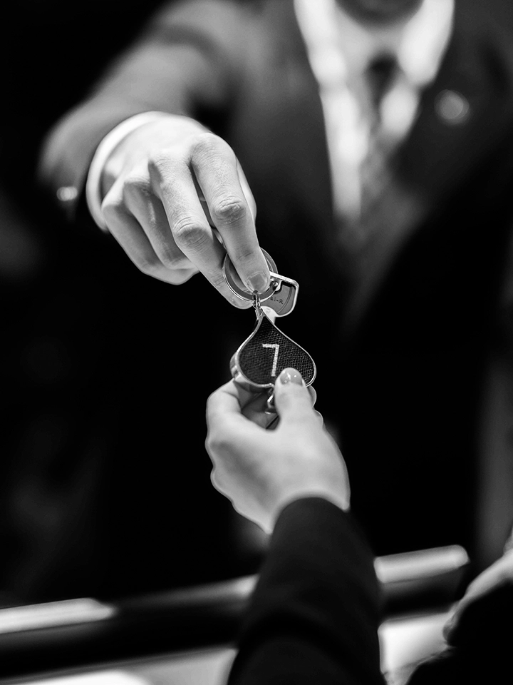 Réceptionniste remettant une clé avec porte-clés en forme de cœur numéroté 7 à un client, dans un environnement professionnel.