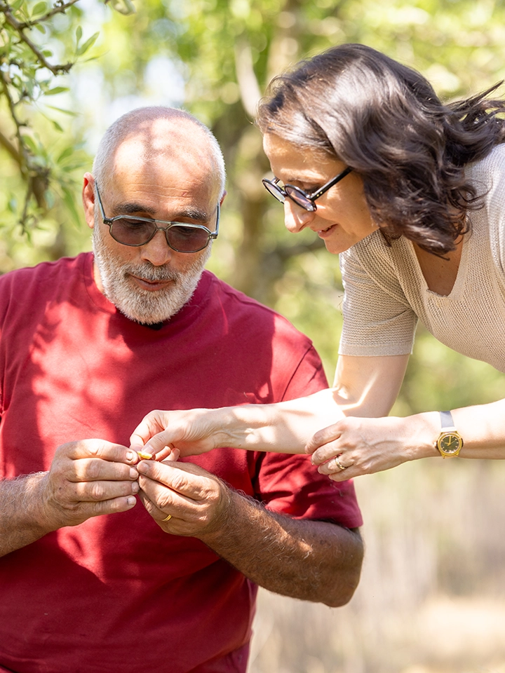 Un homme et une femme inspectent ensemble un petit fruit en extérieur.