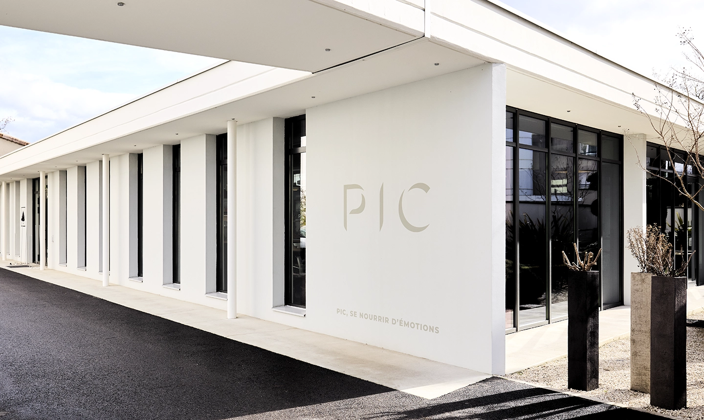 Façade blanche moderne du groupe PIC avec le slogan 'PIC, se nourrir d’émotions'.