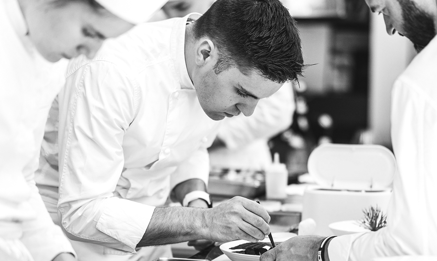 Pâtissier concentré décorant soigneusement un dessert en cuisine professionnelle.