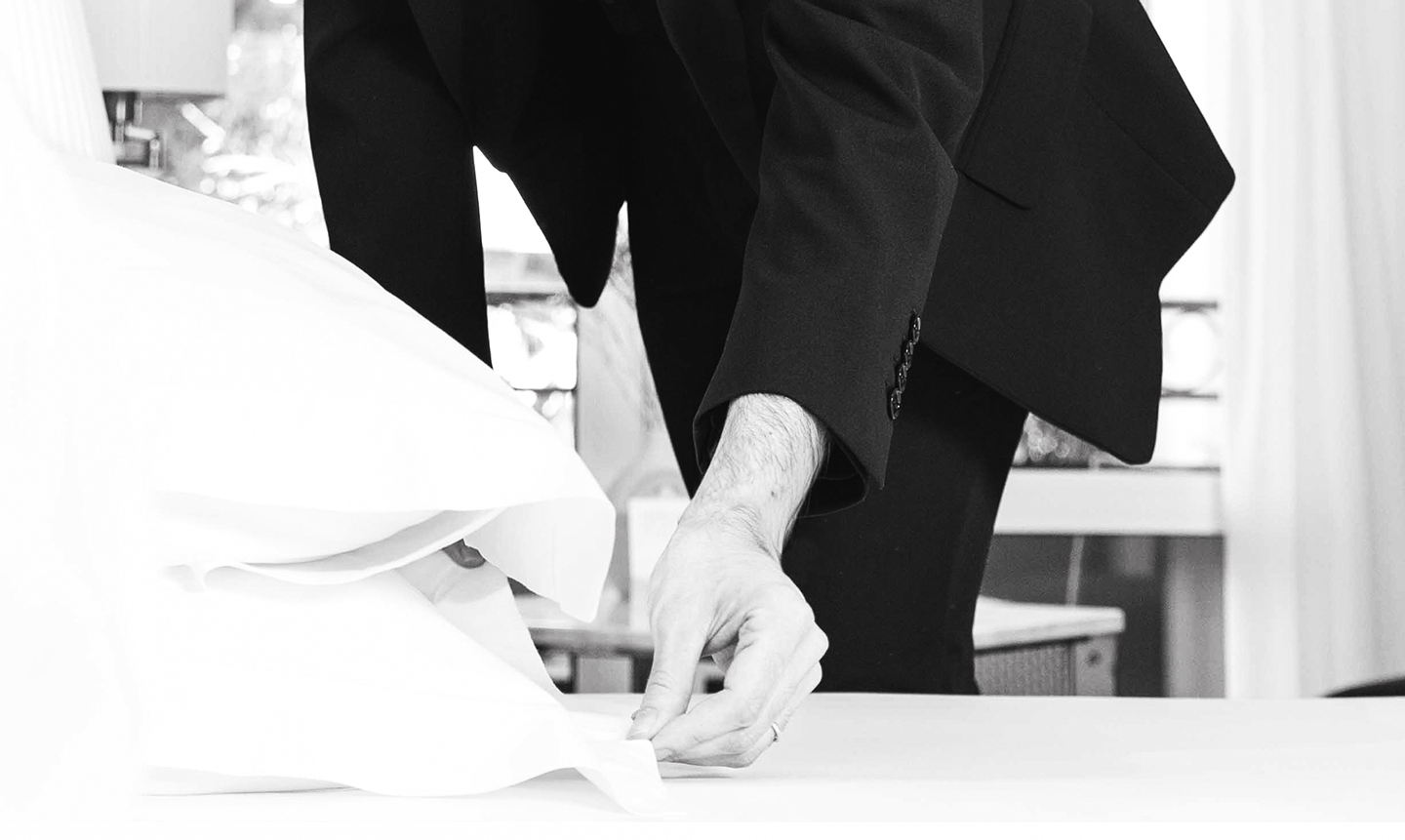 Valet de chambre ajustant les draps dans une chambre élégante.