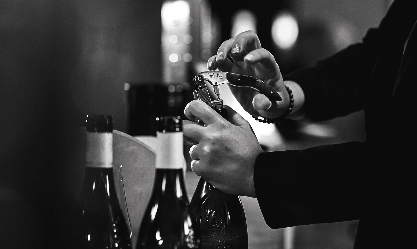 Commis sommelier ouvrant une bouteille de vin avec un tire-bouchon en salle.