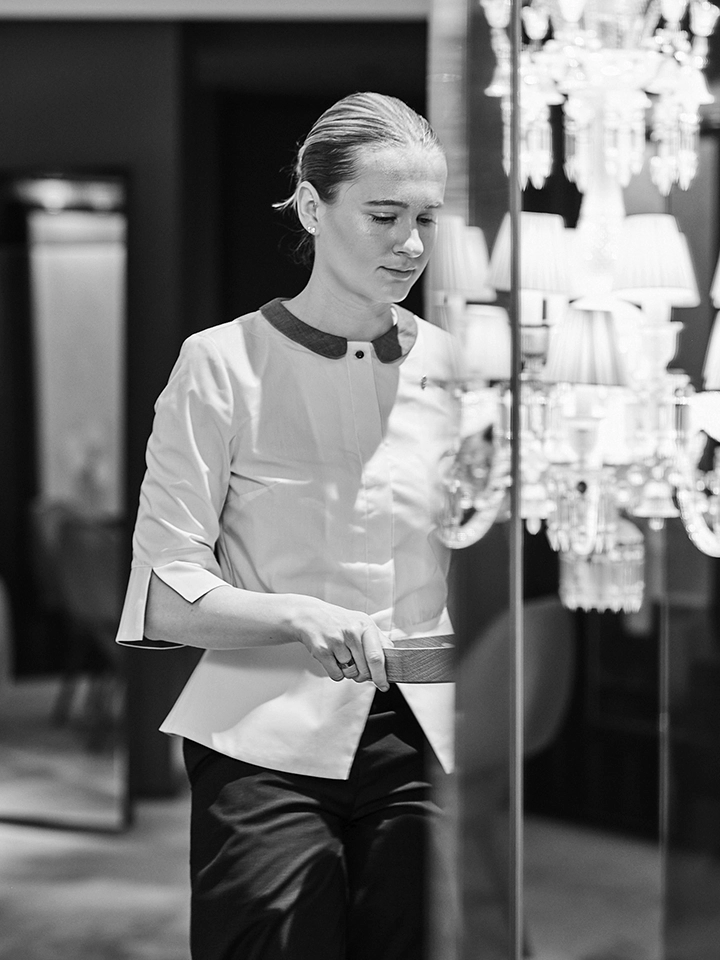 Jeune femme en uniforme professionnel dans un intérieur élégant avec un lustre en verre.