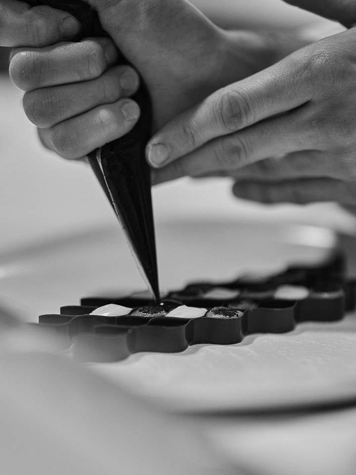 Pâtissier réalisant la finition de chocolats avec une poche à douille.