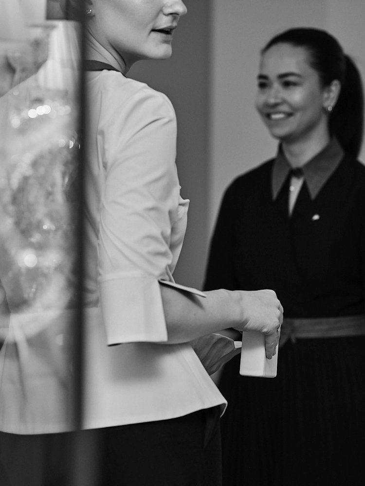 Chef de rang accueillant une cliente et échangeant en salle de restaurant.