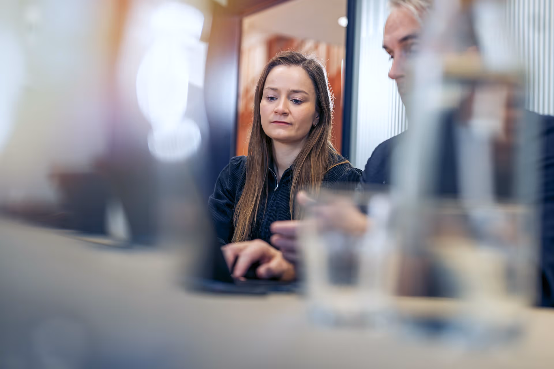 Two people focused on a laptop during a discussion in an office setting.