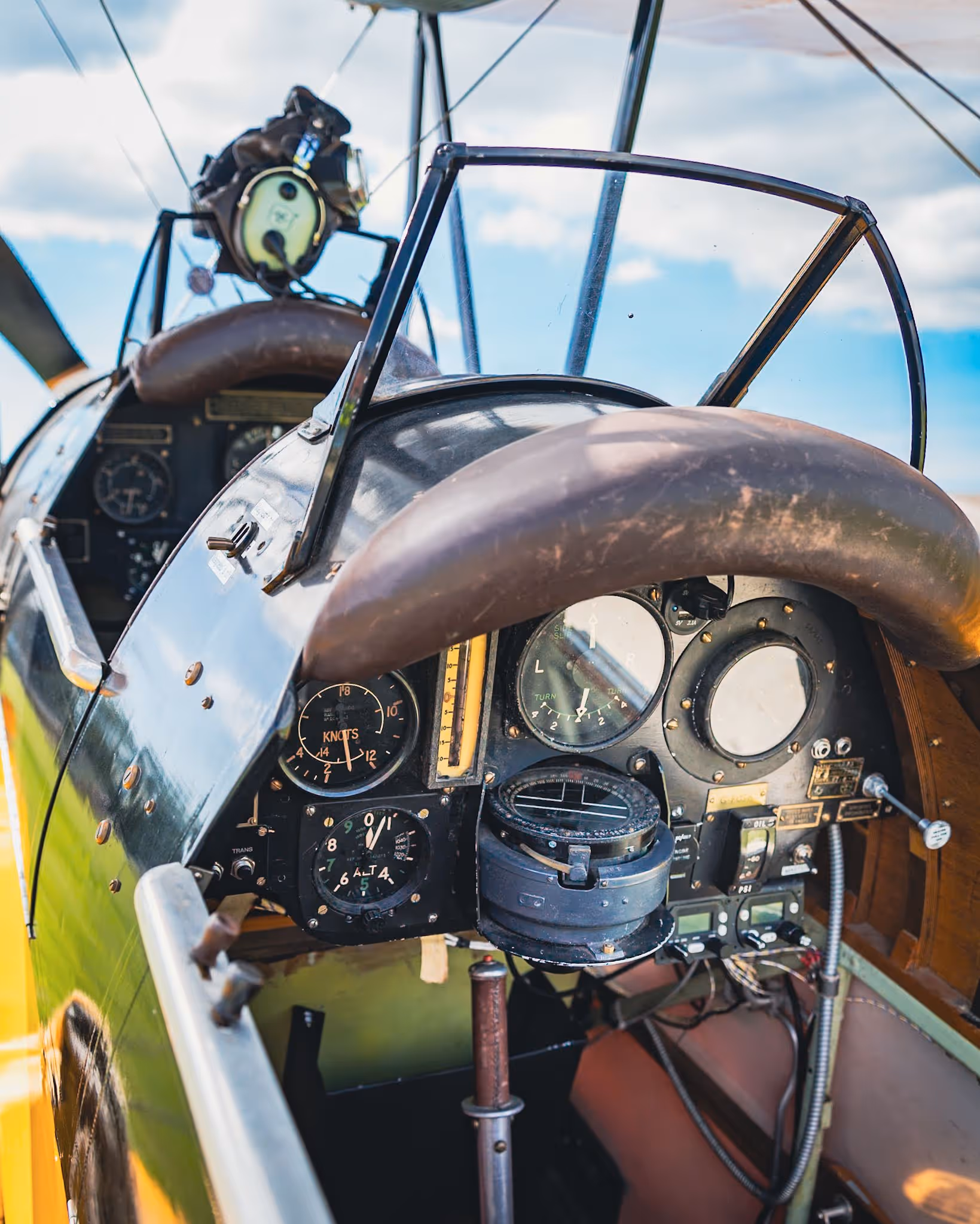 Cockpit of an old airplane, showing various dials, gauges, and controls under a clear sky.