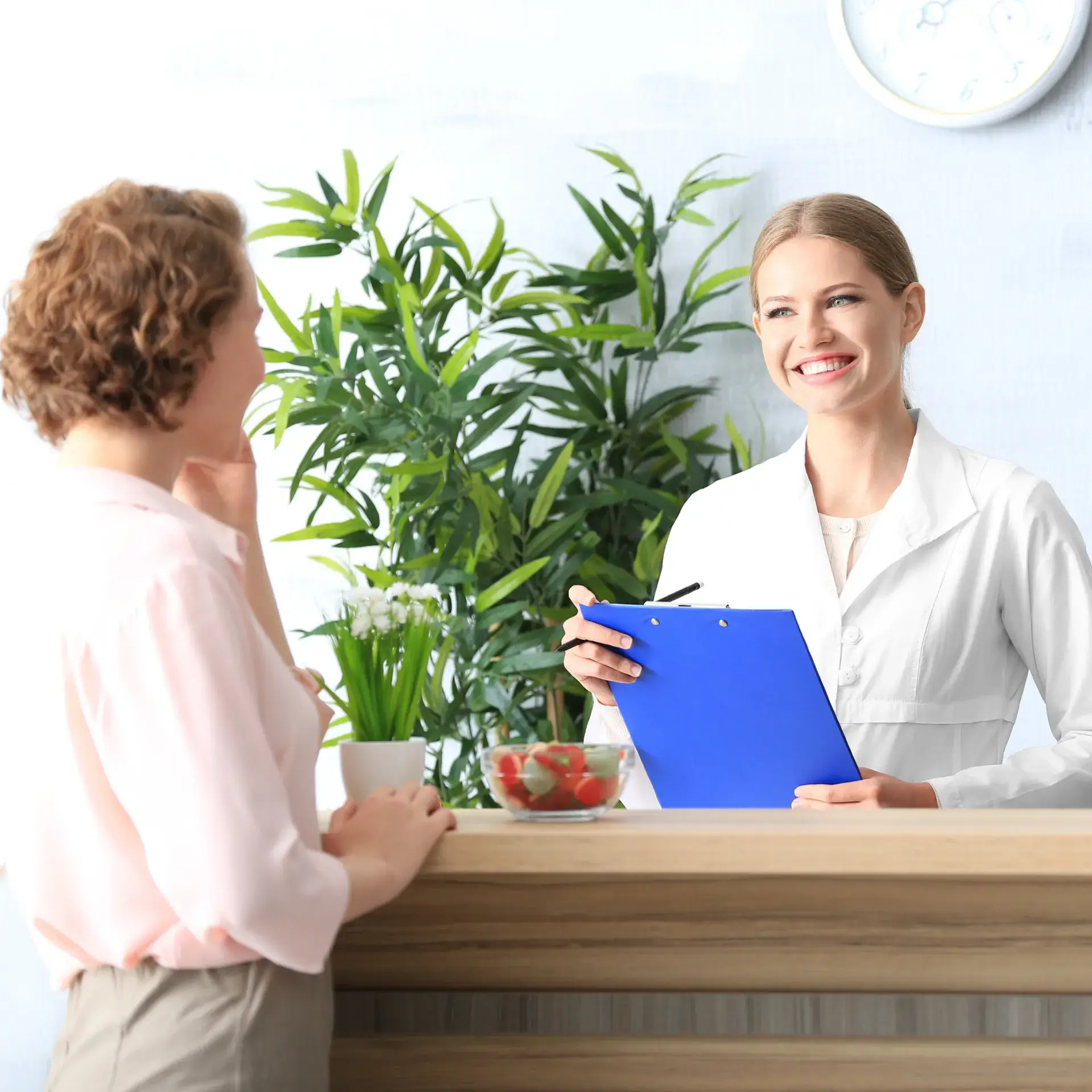 A woman sitting at a desk talking to another woman.