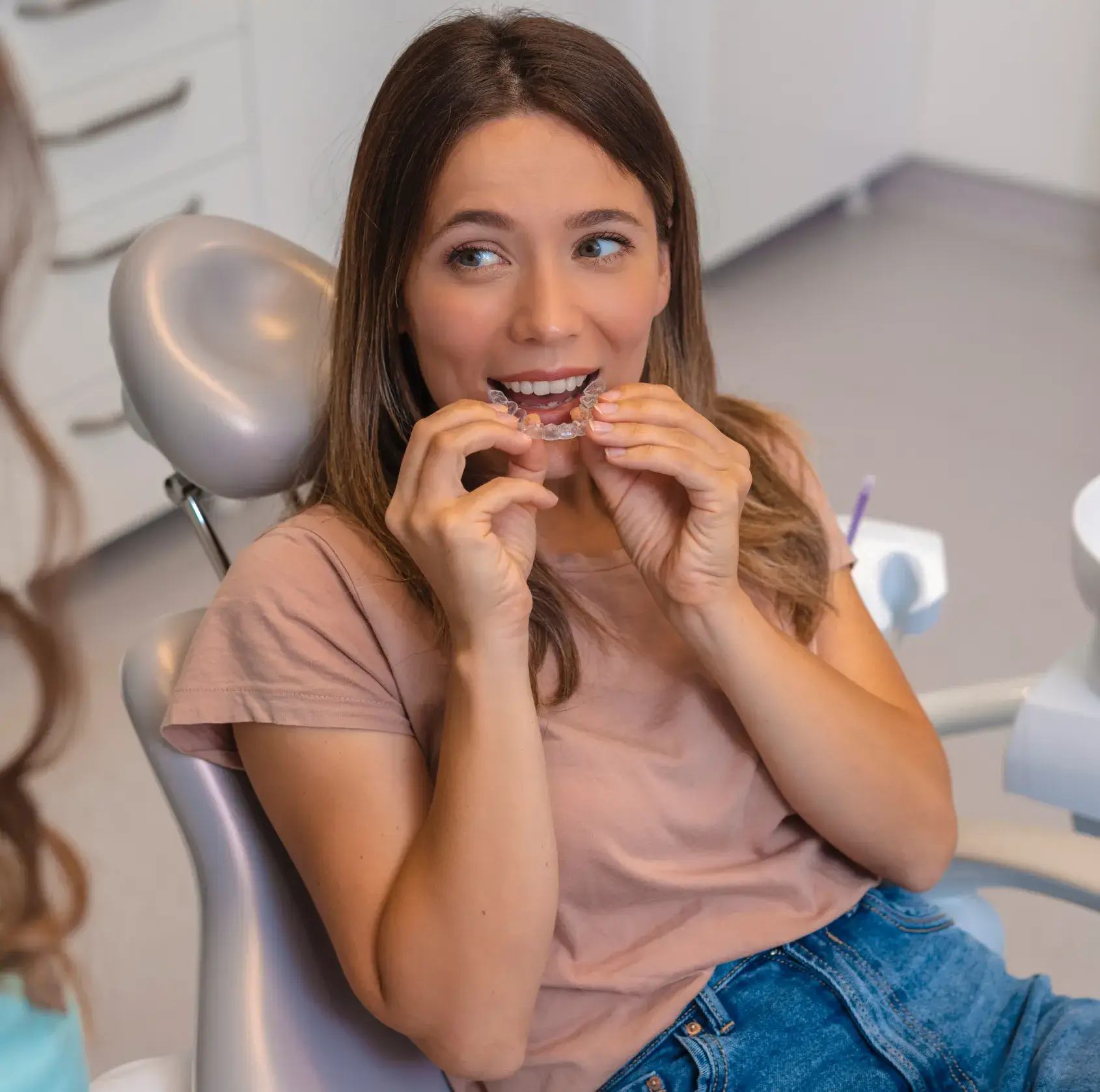 A woman sitting in a chair with a toothbrush in her mouth.
