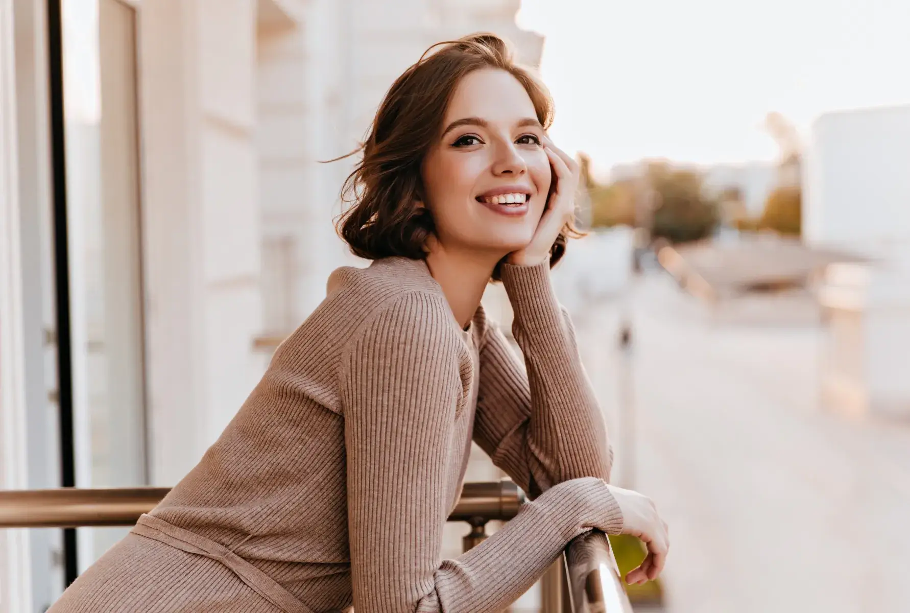 A woman leaning on a rail smiling at the camera.
