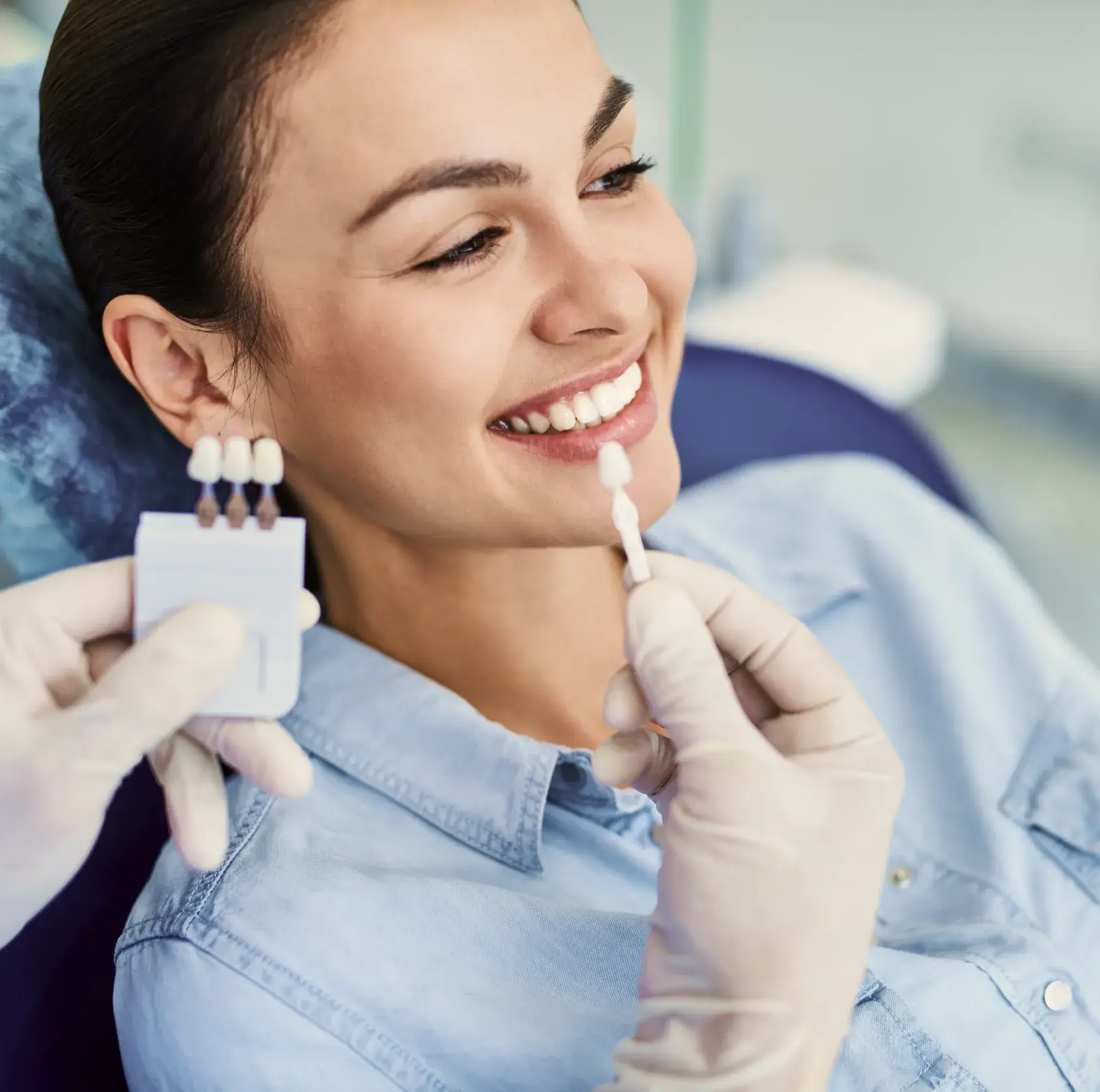 A woman smiling while holding a toothbrush in her mouth.