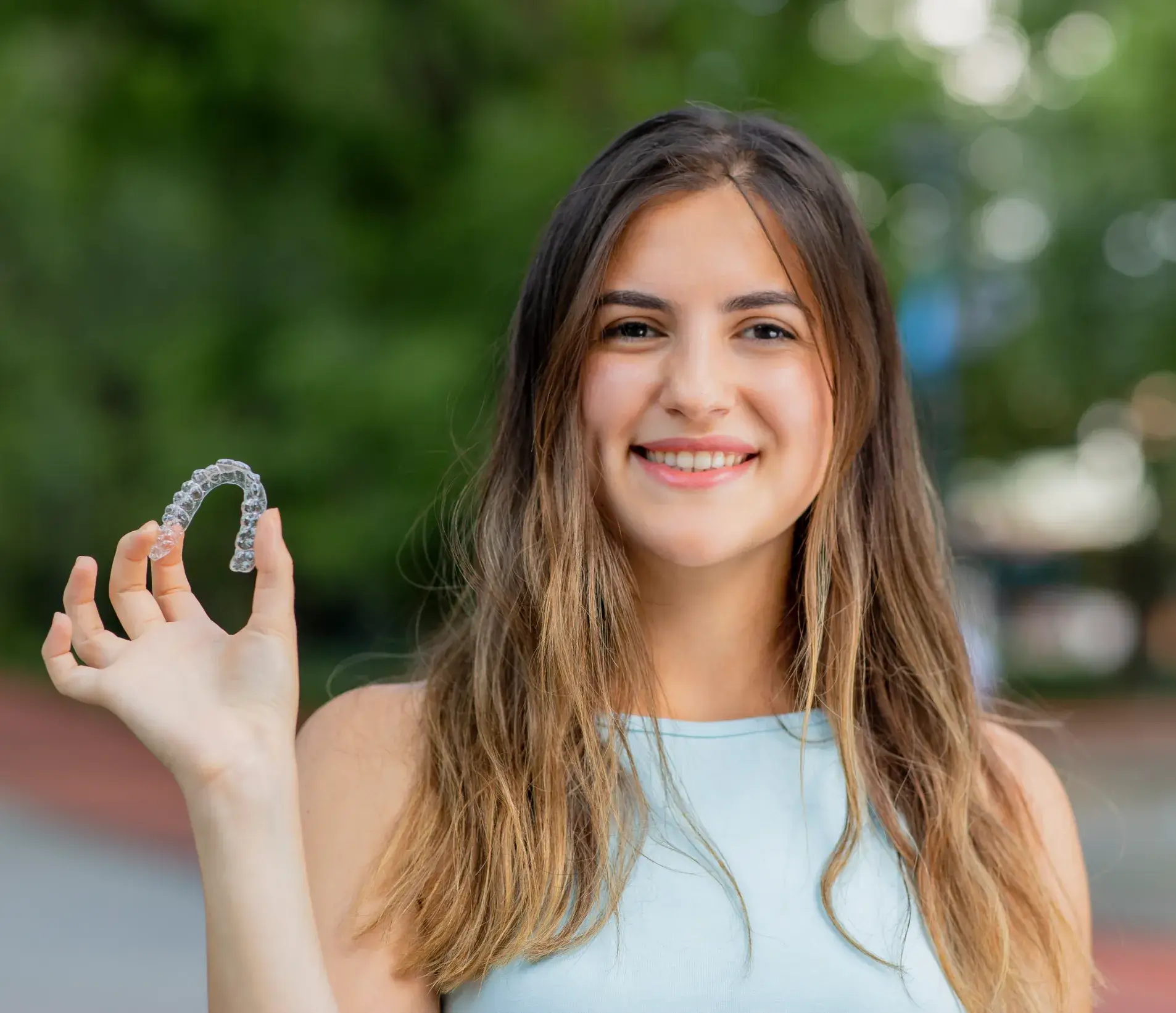 A woman holding up a diamond ring in front of her face.
