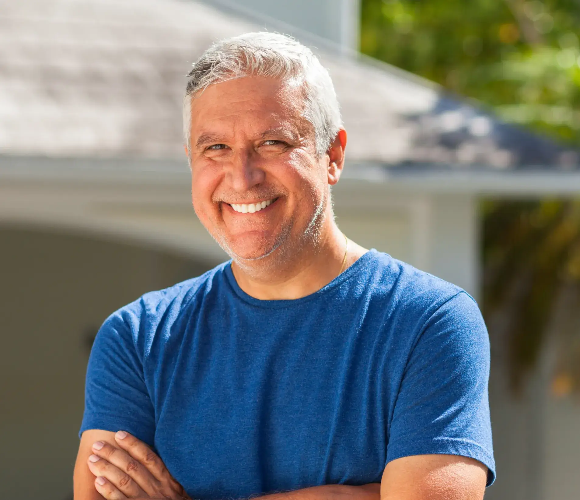 A man in a blue shirt standing with his arms crossed.