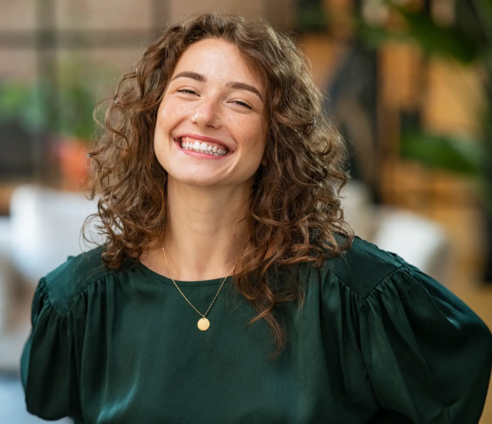 A woman with curly hair smiling at the camera.