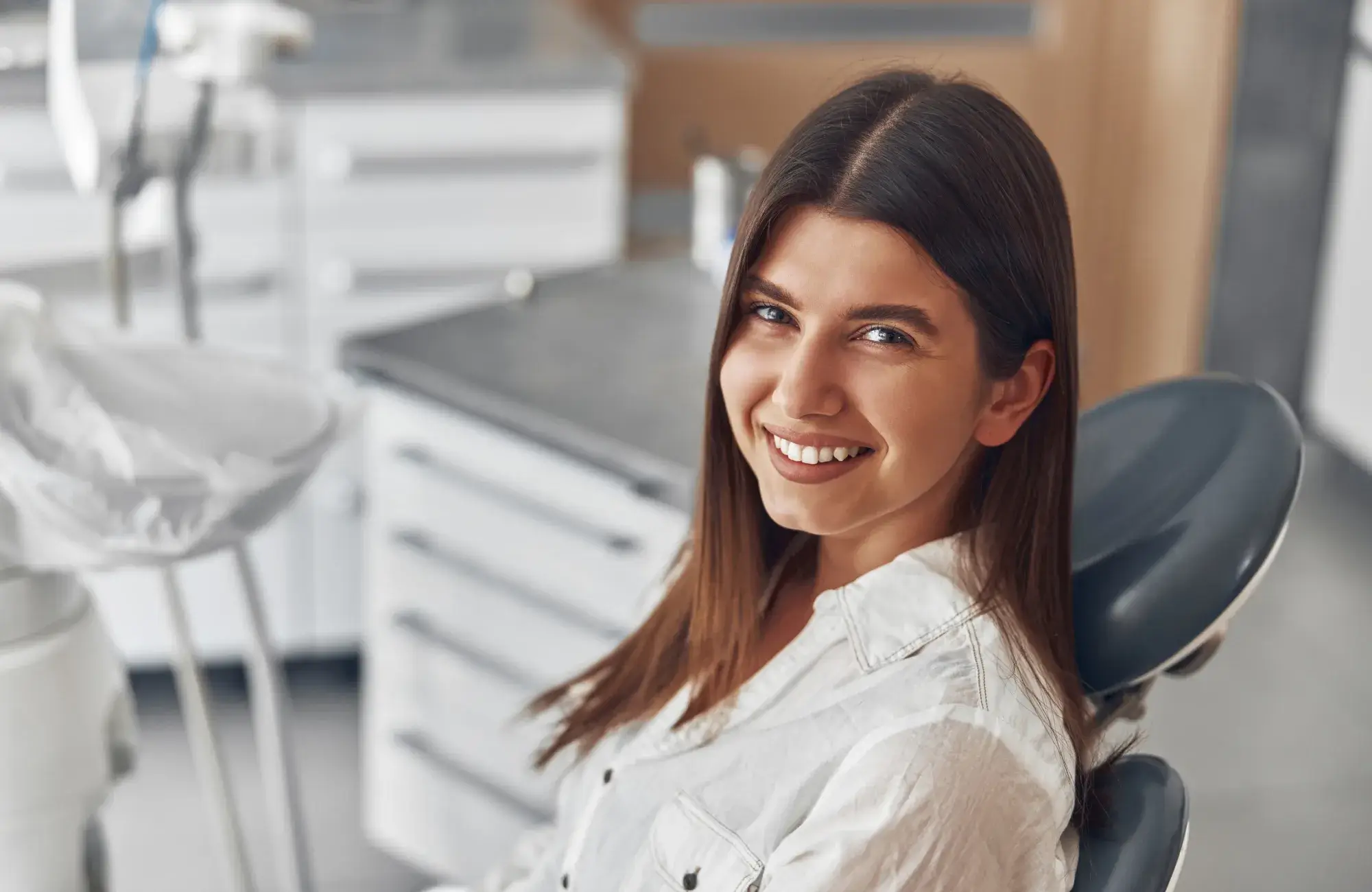 A woman sitting in a dentist chair smiling.