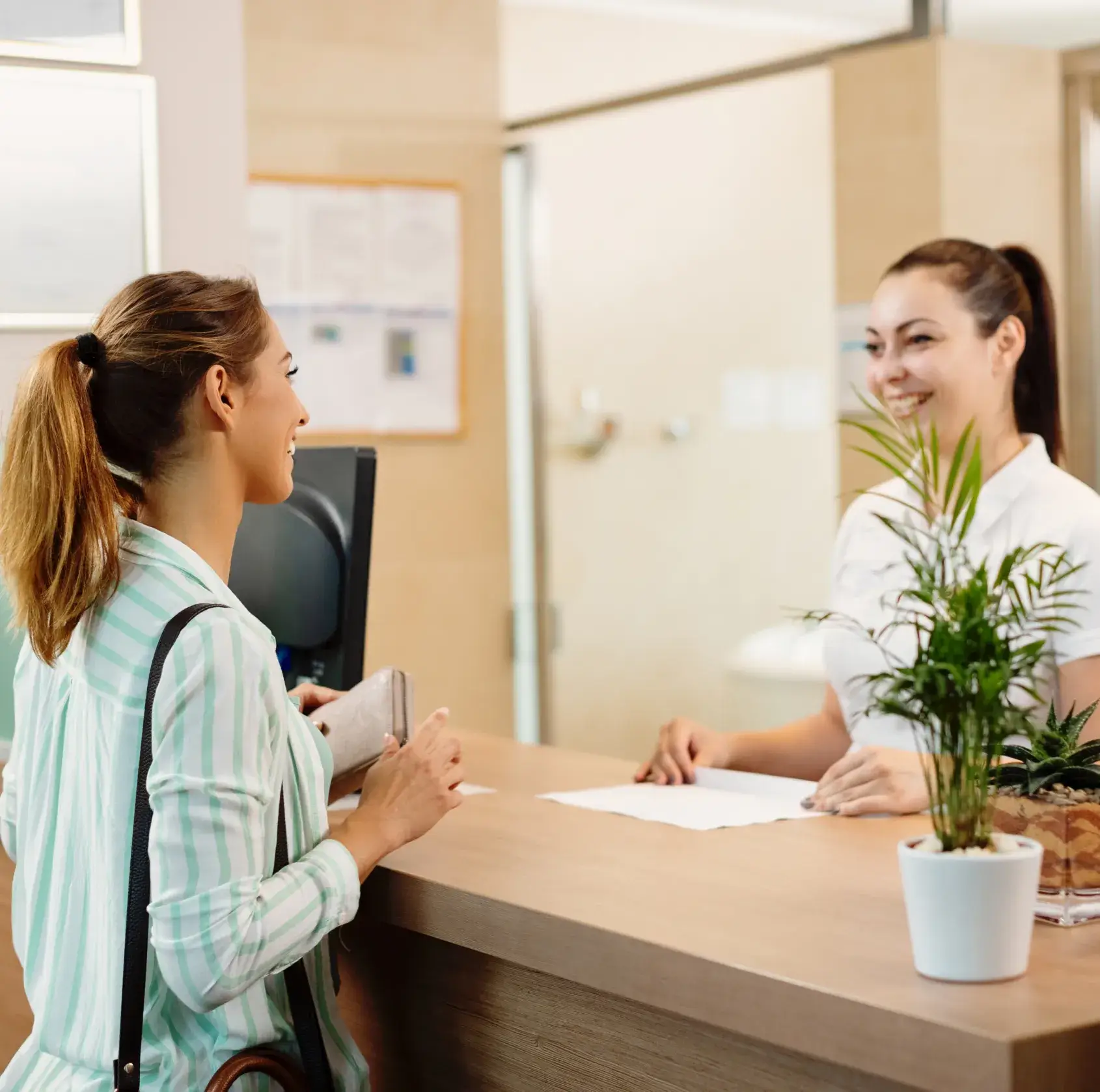 A woman sitting at a desk talking to another woman.