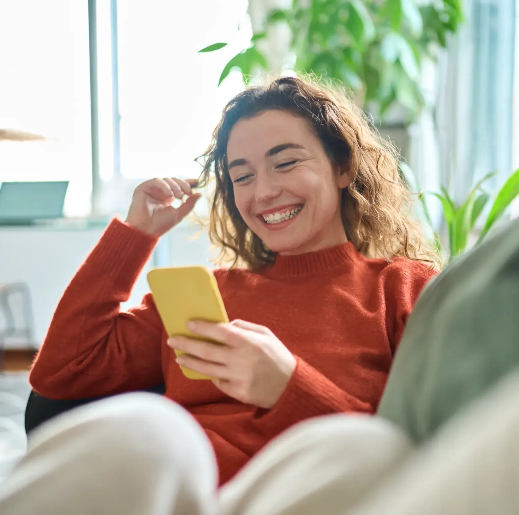A woman sitting on a couch looking at a cell phone.