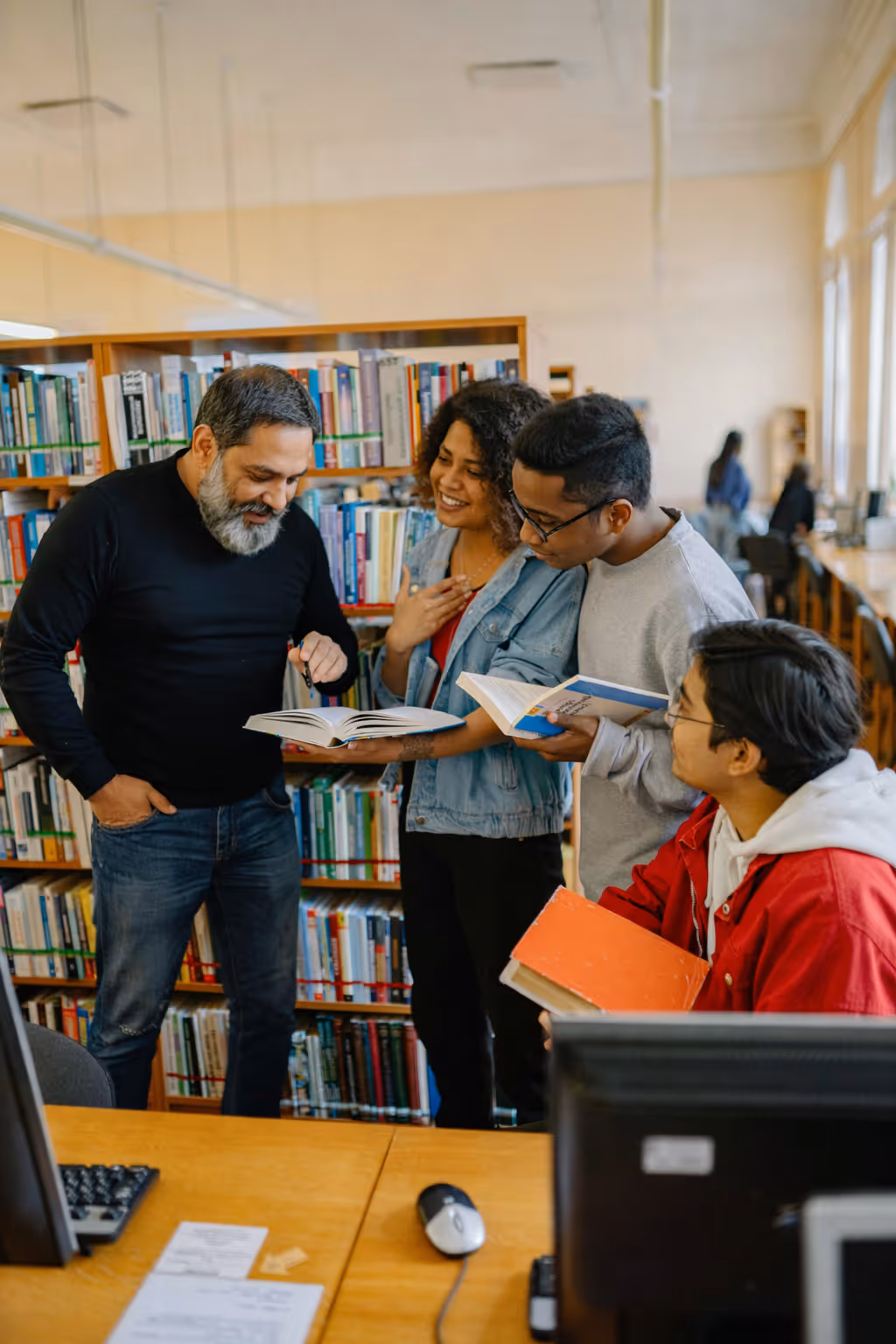A group of people discussing over open books in a library