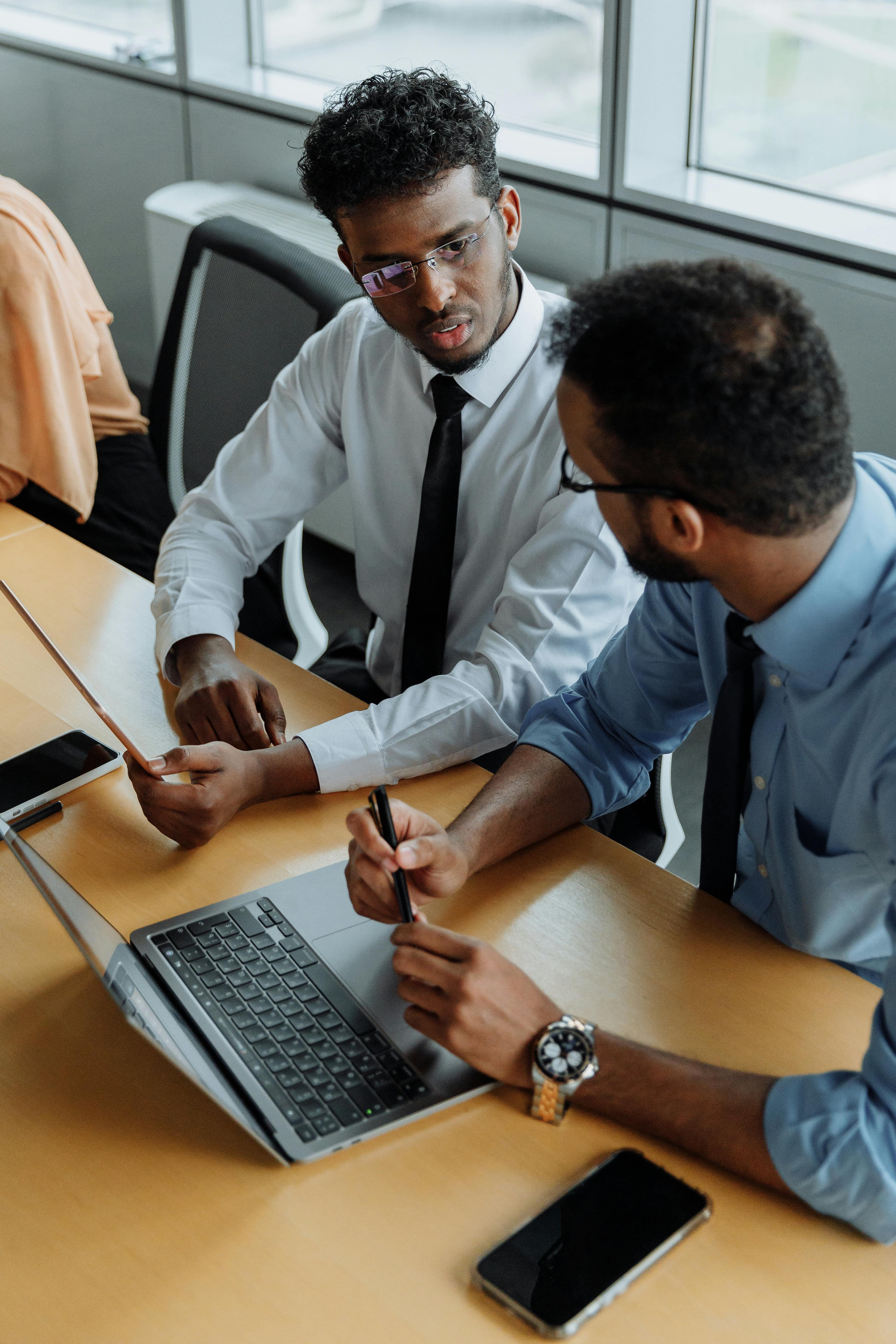 Two professionals collaborating over a laptop and documents at a conference table