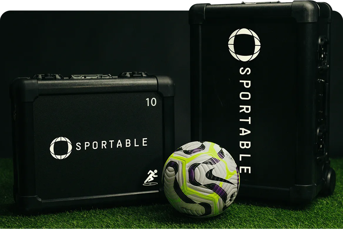 Two black cases labeled 'SPORTABLE' and a Nike soccer ball with neon yellow and purple accents on green turf.