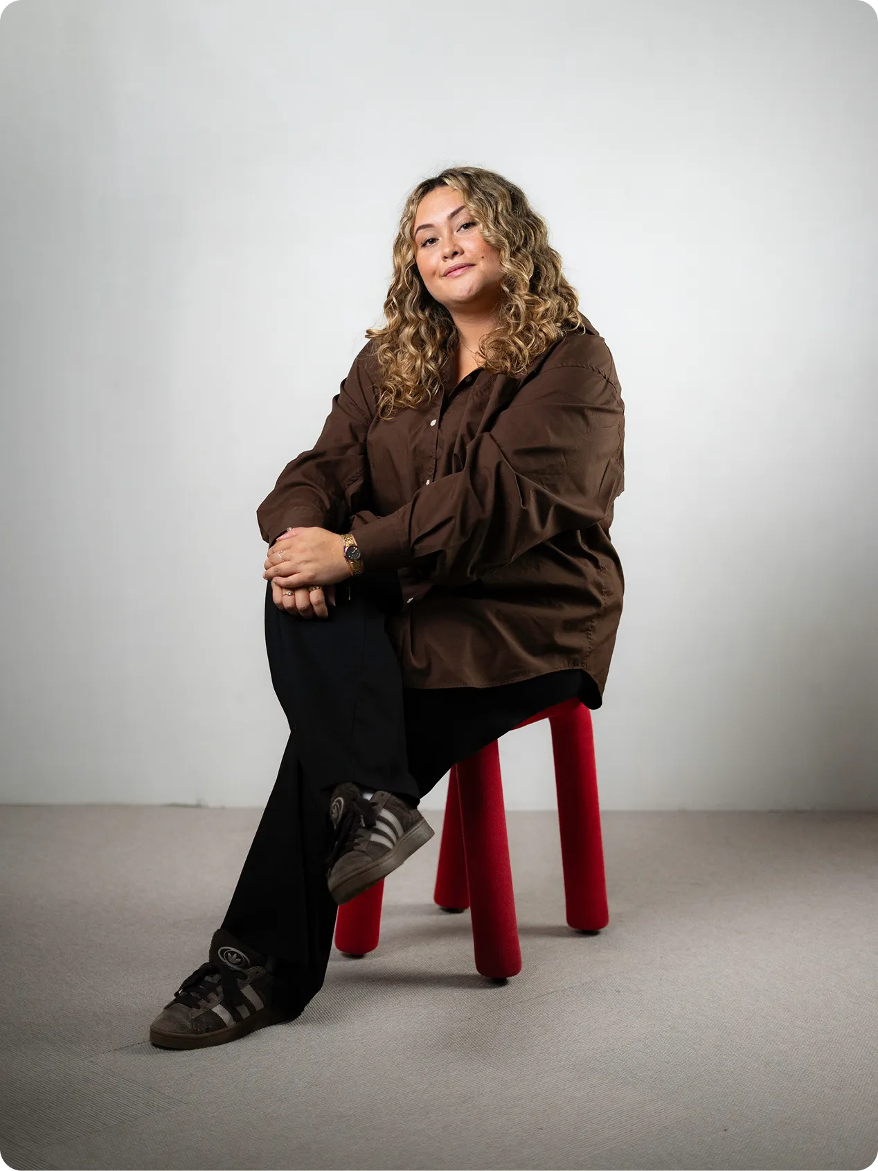 Casandra Sohlström, UX/UI & web designer, studio portrait sitting on a red stool.