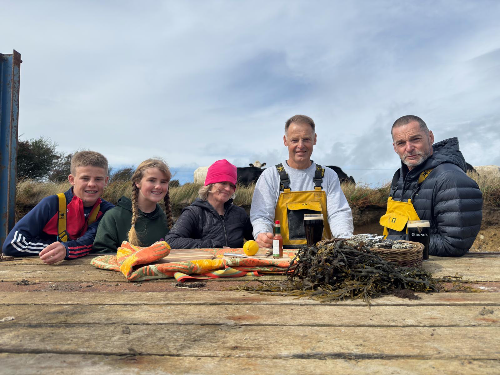 5 People sitting at a table with Oysters in front of them