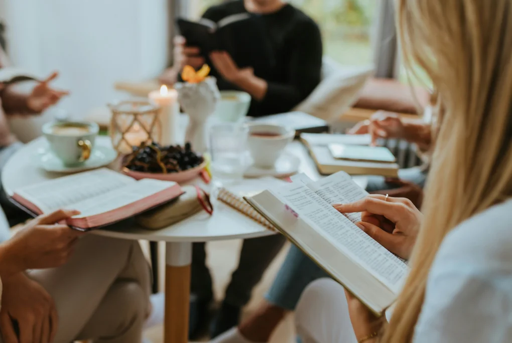 Small group gathered around a table, reading books and drinking tea during a study session.