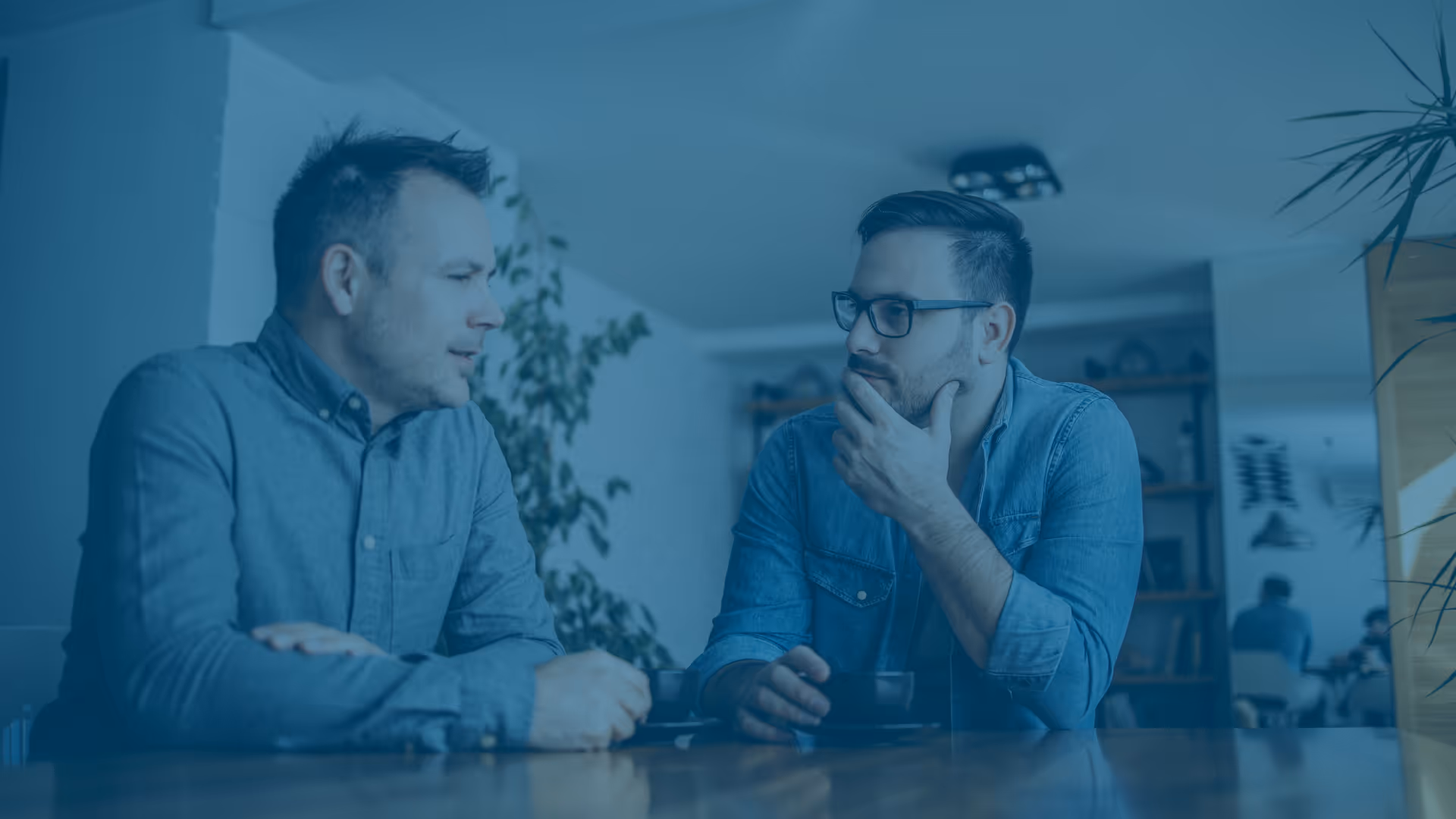 Two men sitting at a table, in conversation with each other