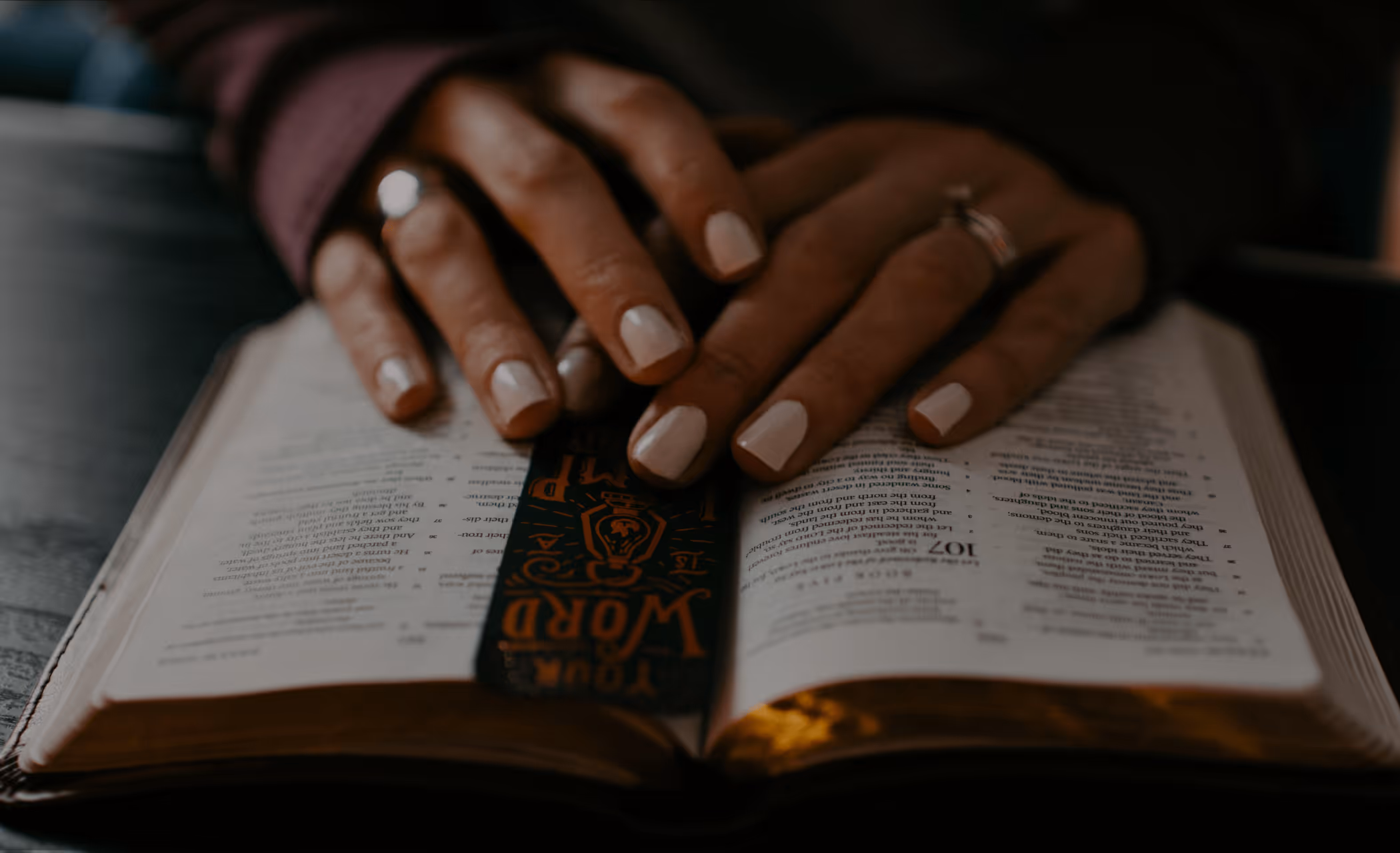 Hands laying on top of an open Bible