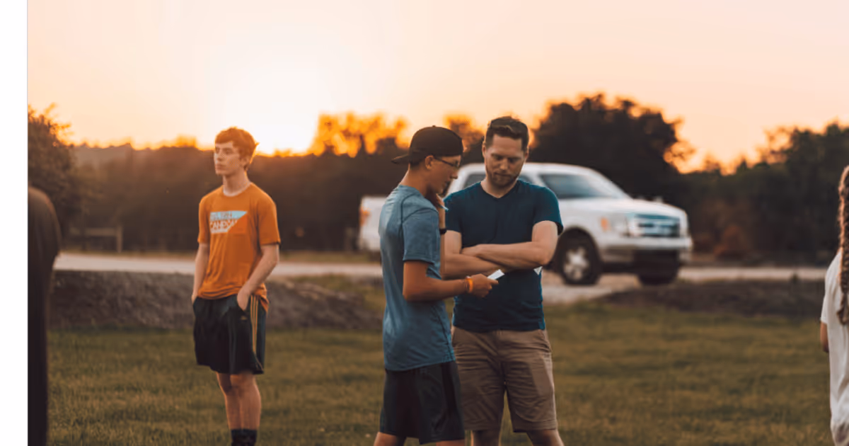 Men talking outside, white truck and sunset behind them