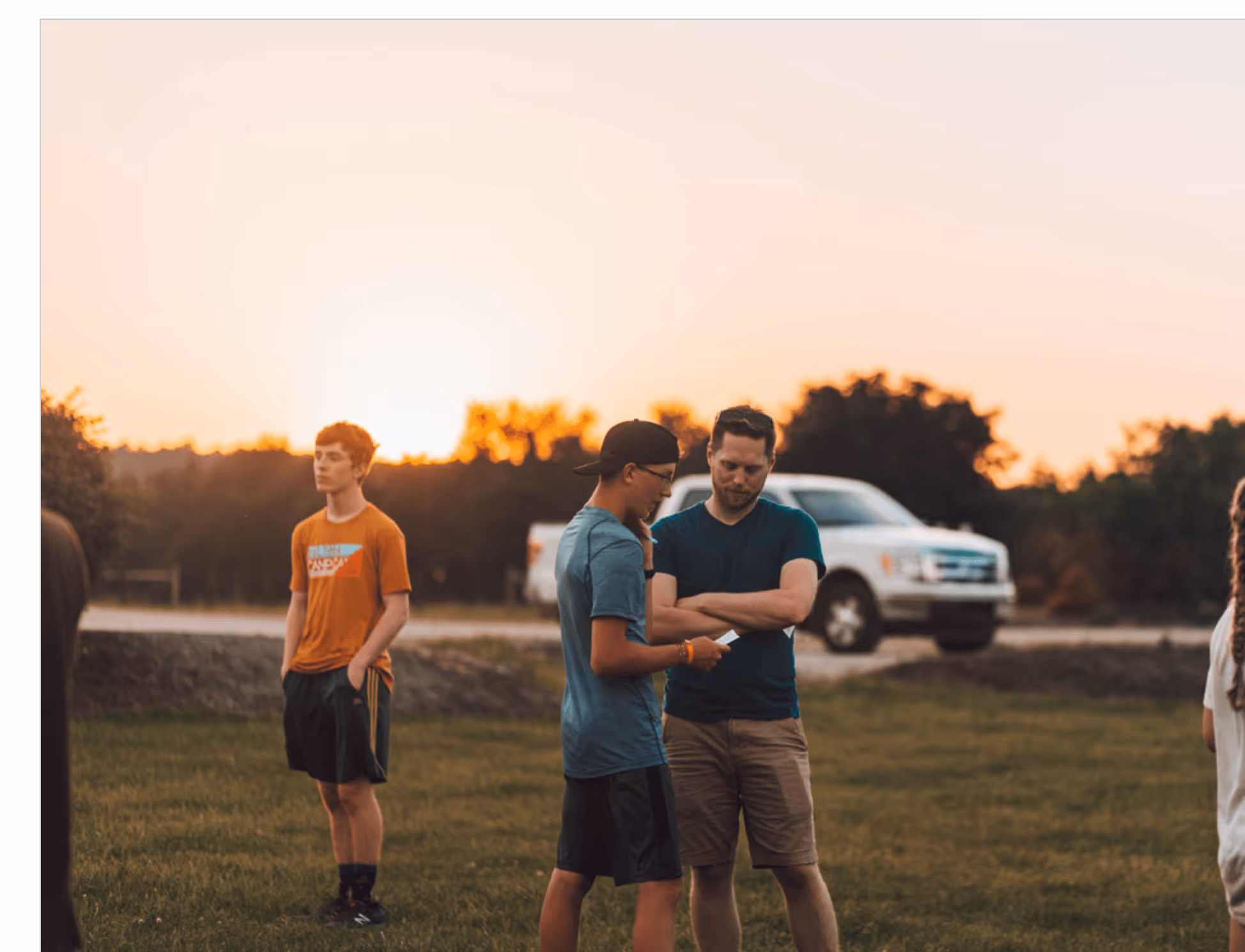 Men talking outside, white truck and sunset behind them