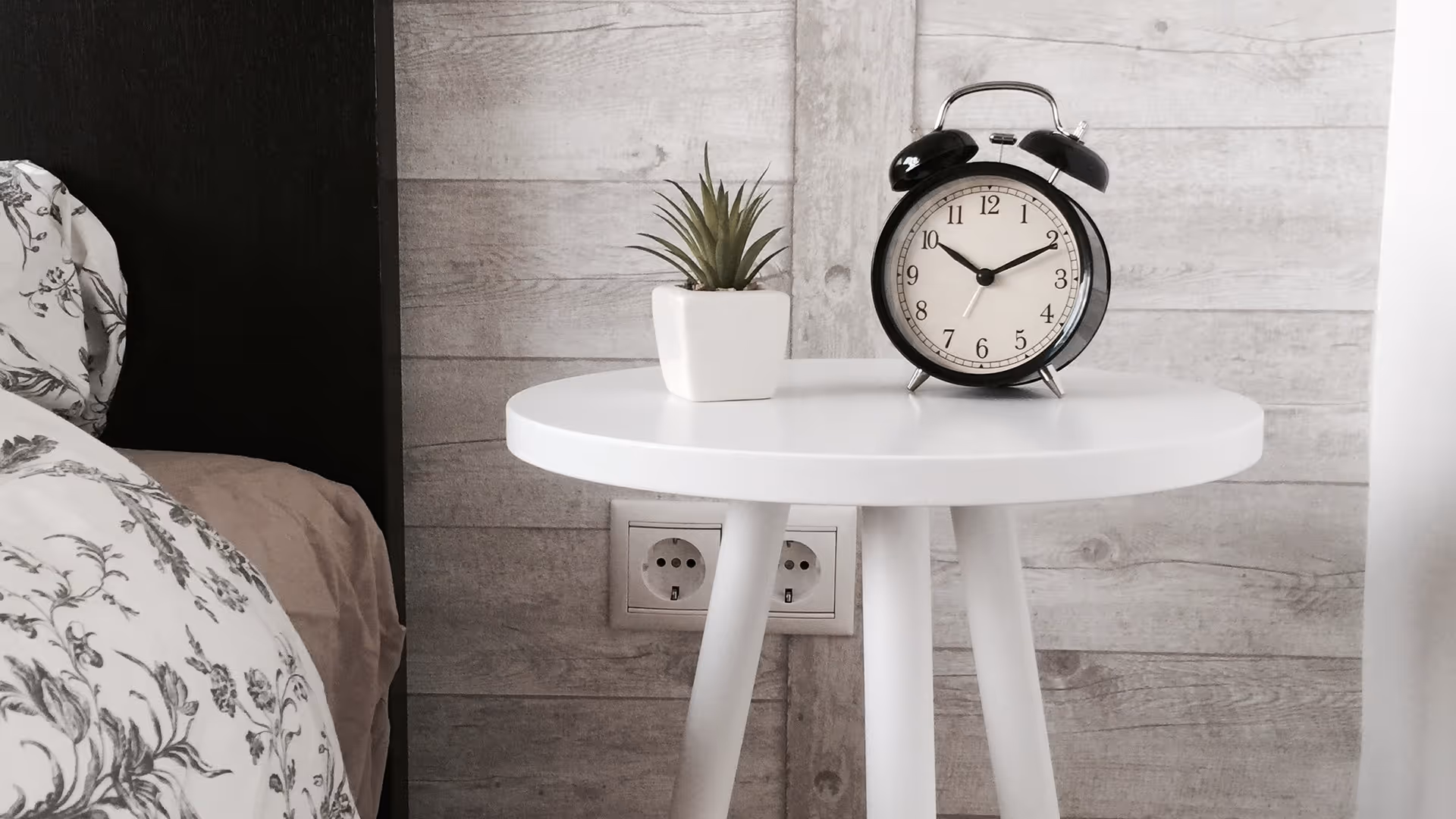 Black clock on white bedside table