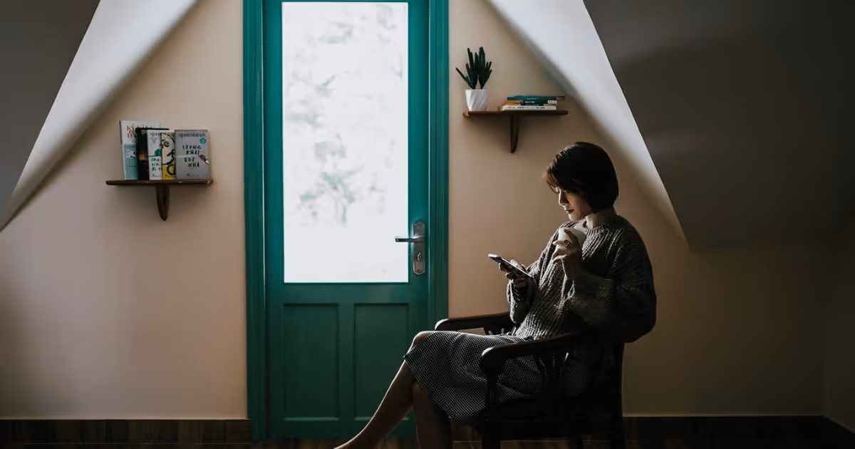 Woman looking at her phone, sitting by door
