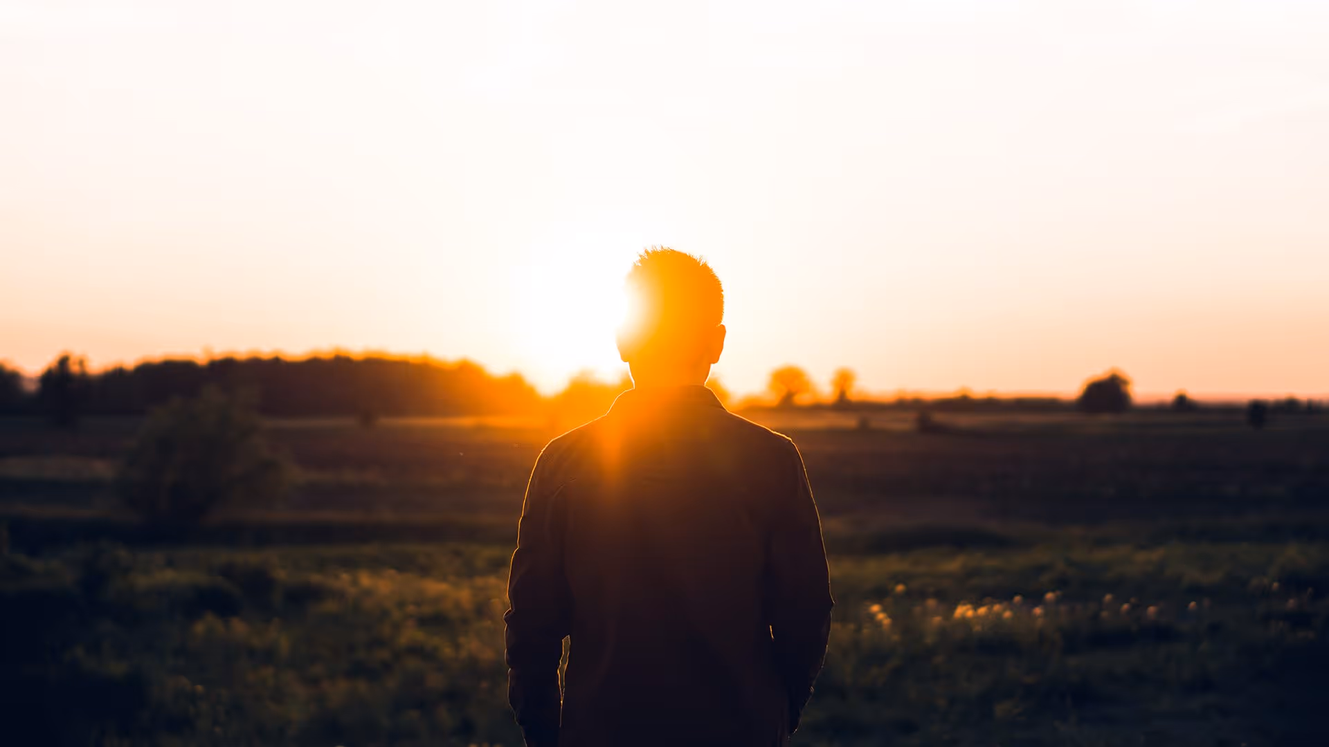 Man standing open field during sunset
