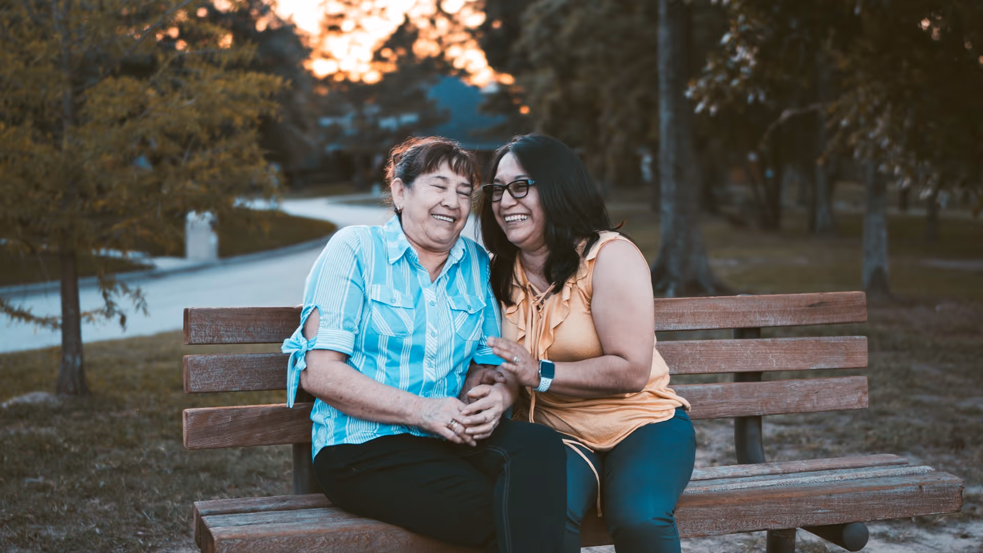 Mom and Daughter sitting on a bench laughing
