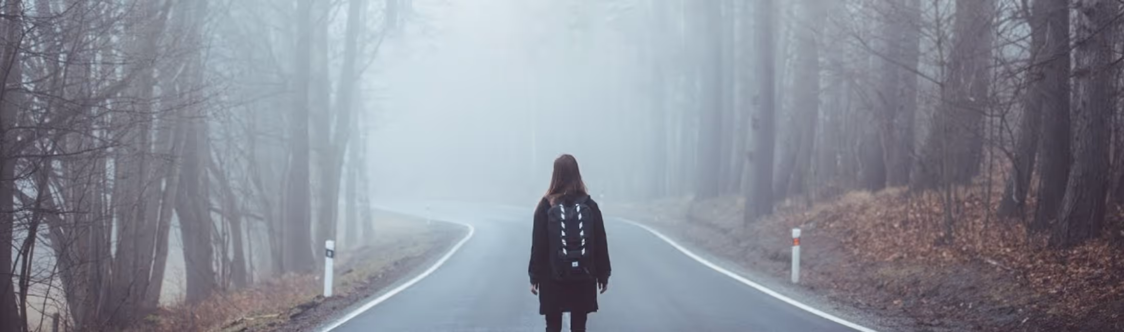 Woman with backpack standing in the middle of forest trail